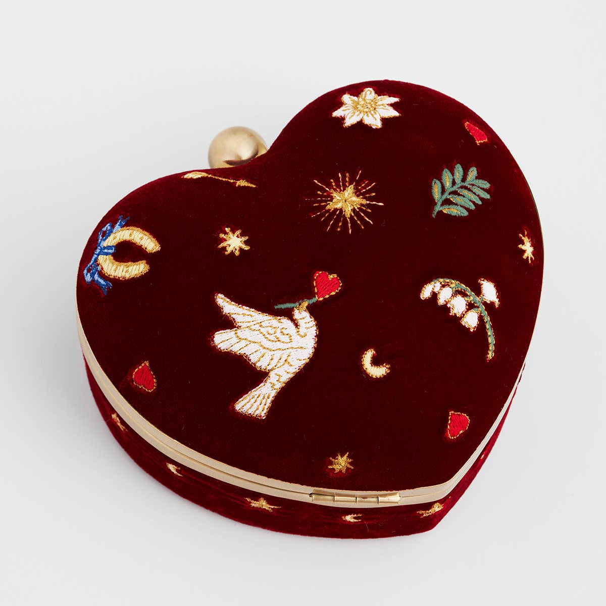 Close up of embroidered dove, moon and flower motifs on red velvet