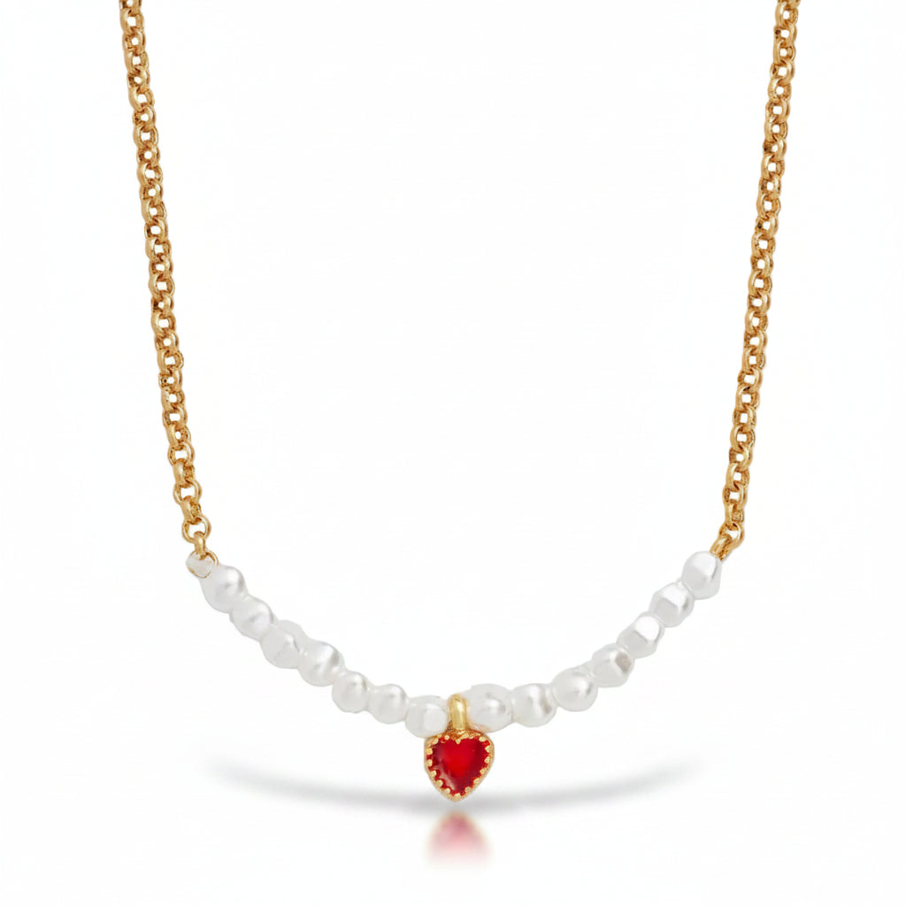 Close-up of the red enamel heart charm and pearls on the gold chain