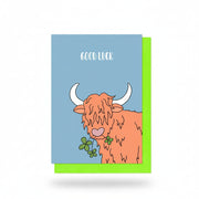 Good Luck card with an orange Highland cow holding a green clover