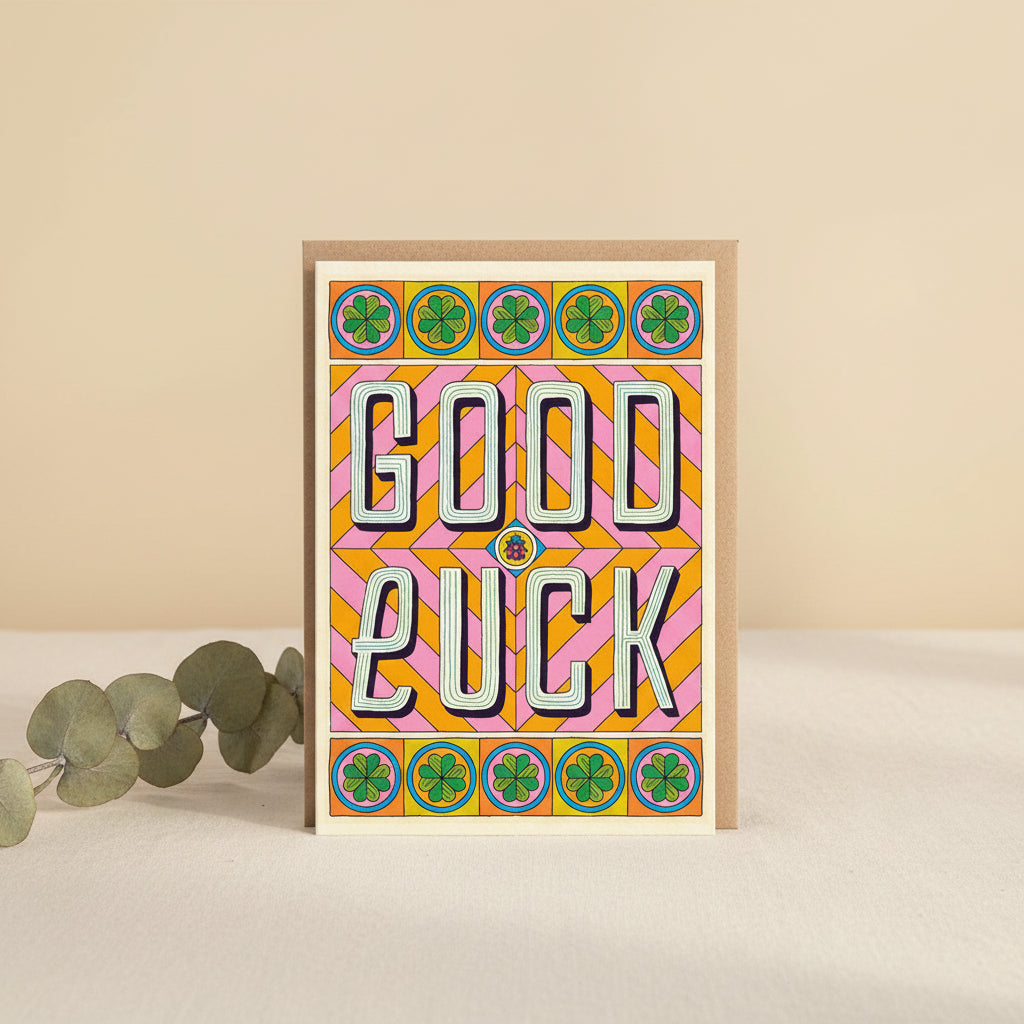 Colorful 'Good Luck' card with geometric patterns and four-leaf clovers on a white background.