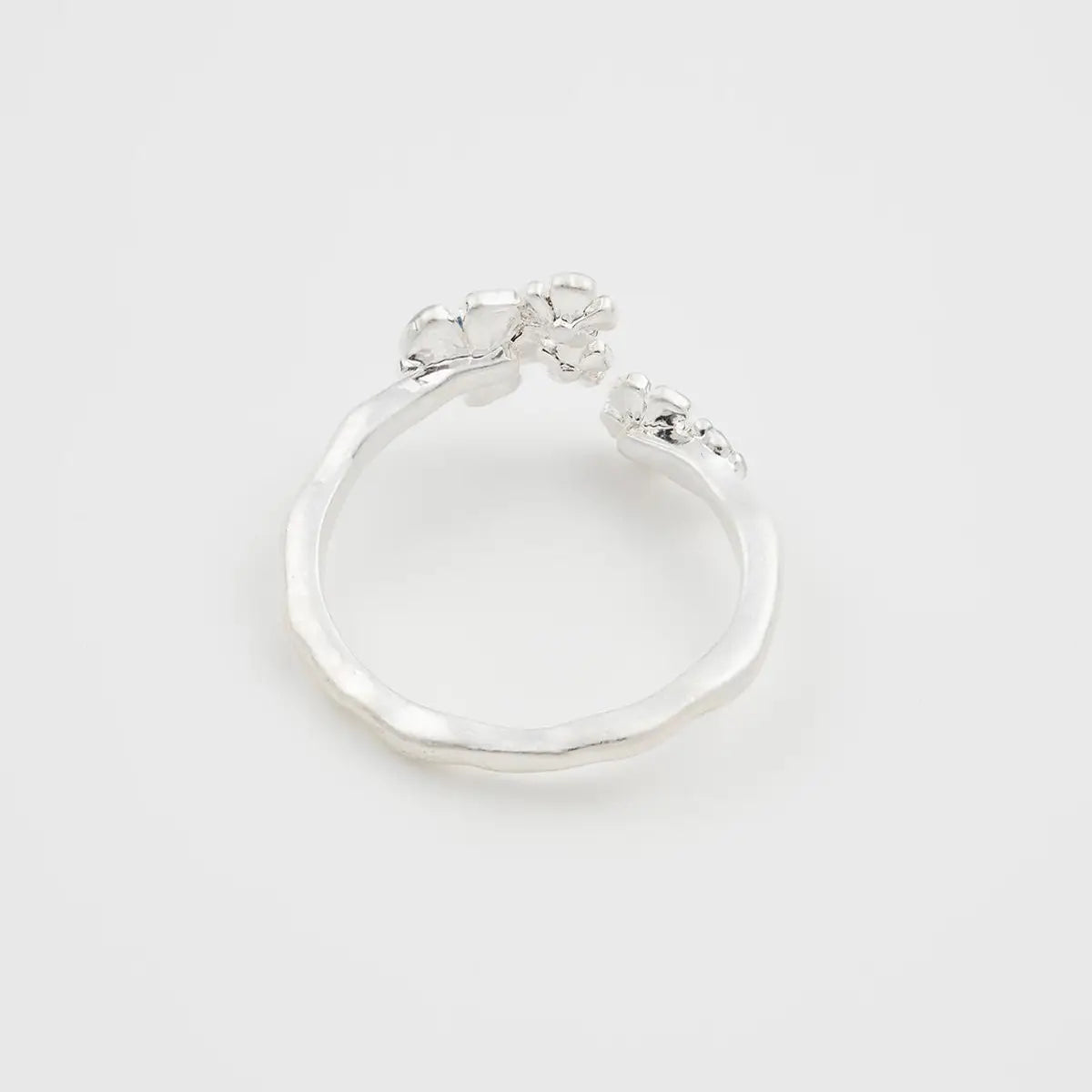 Back angle of floral silver ring showing open band and organic twig-like texture.