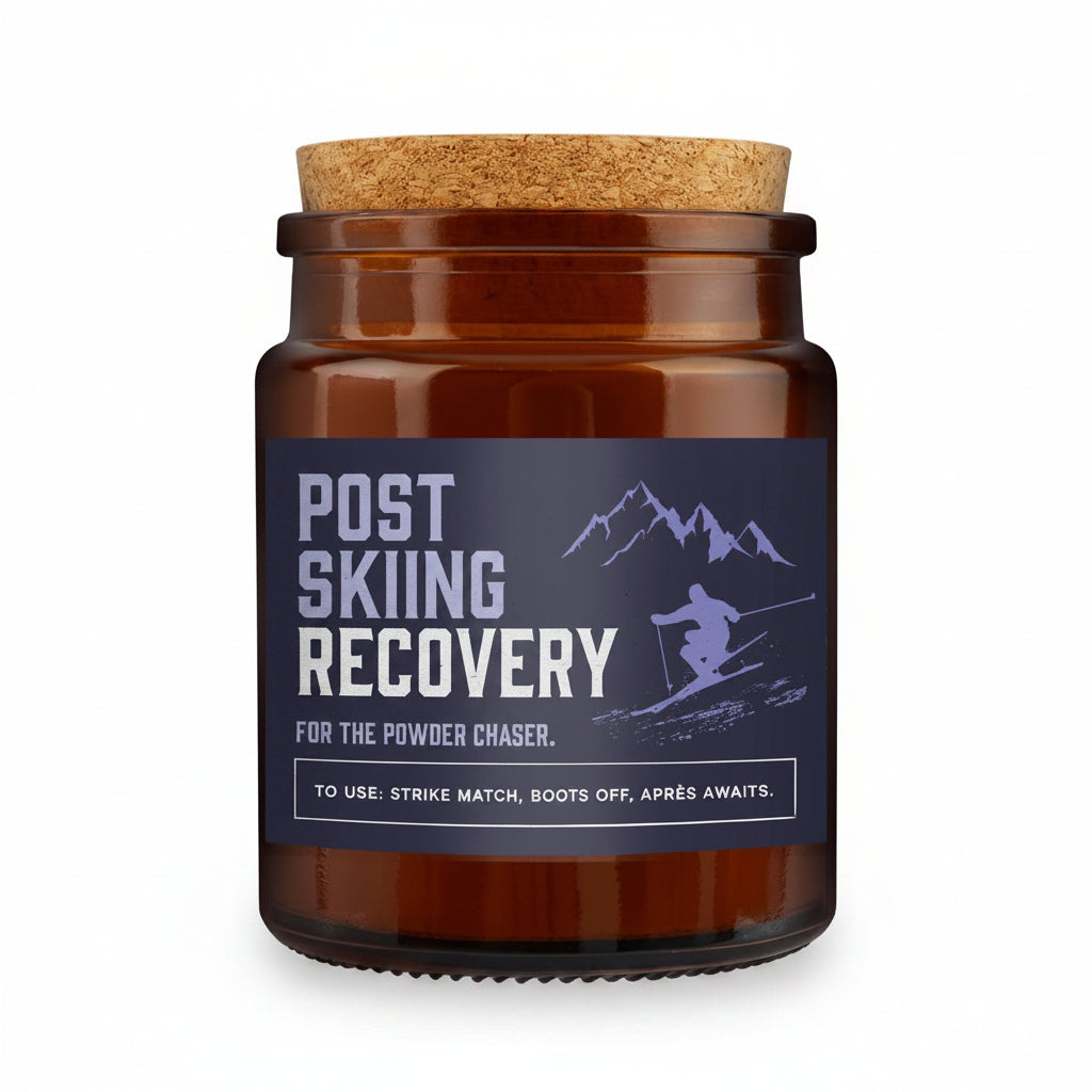 An amber glass jar candle with a cork lid and a dark navy label reading 'POST SKIING RECOVERY' with a skier graphic, set against a snowy mountain background.