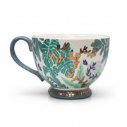 Porcelain foliage mug with blue handle and intricate botanical design.