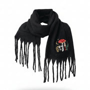 Front view of person wearing the black Forage Scarf with embroidered red toadstool and forest design, wrapped around the neck with fringe detail showing.