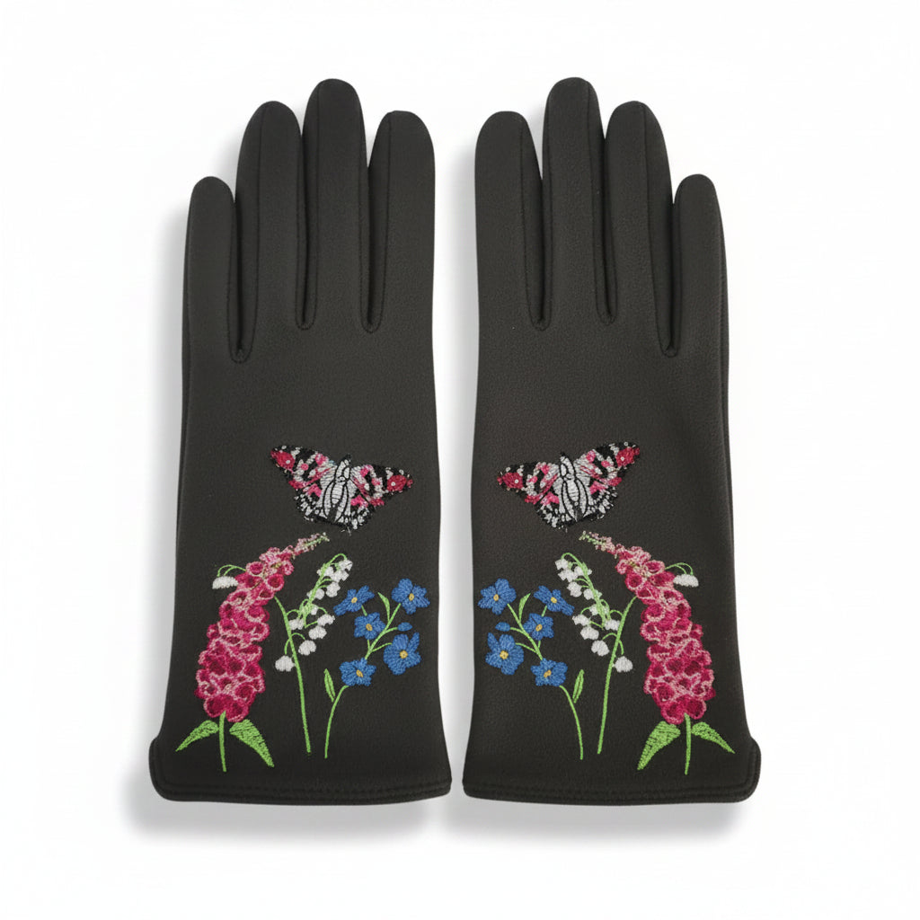 Flat lay of both gloves with vivid floral and butterfly embroidery on the outer side, including pink foxgloves, lily of the valley, cornflowers, and two pink butterflies.