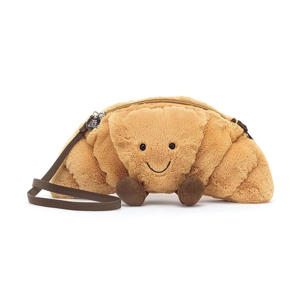 Coffee Date Companion: The Jellycat Amuseable Croissant Bag perched on a cafe table next to a steaming latte, capturing its essence as a stylish and functional accessory for coffee lovers.