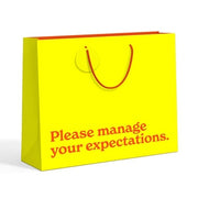 Manage Your Expectations large yellow gift bag - angled view on white background