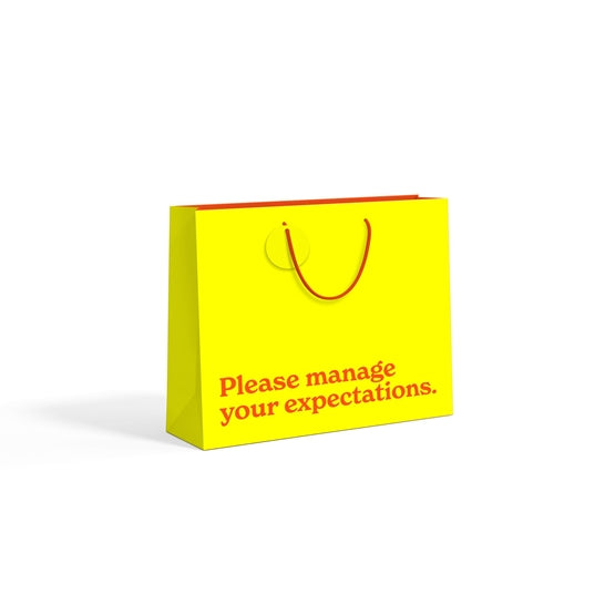 Manage Your Expectations large yellow gift bag - angled view on white background