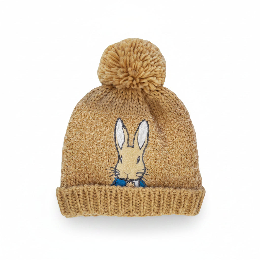 Child wearing Peter Rabbit™ hat and gloves, hands covering face – cute neutral knit beanie set for kids.