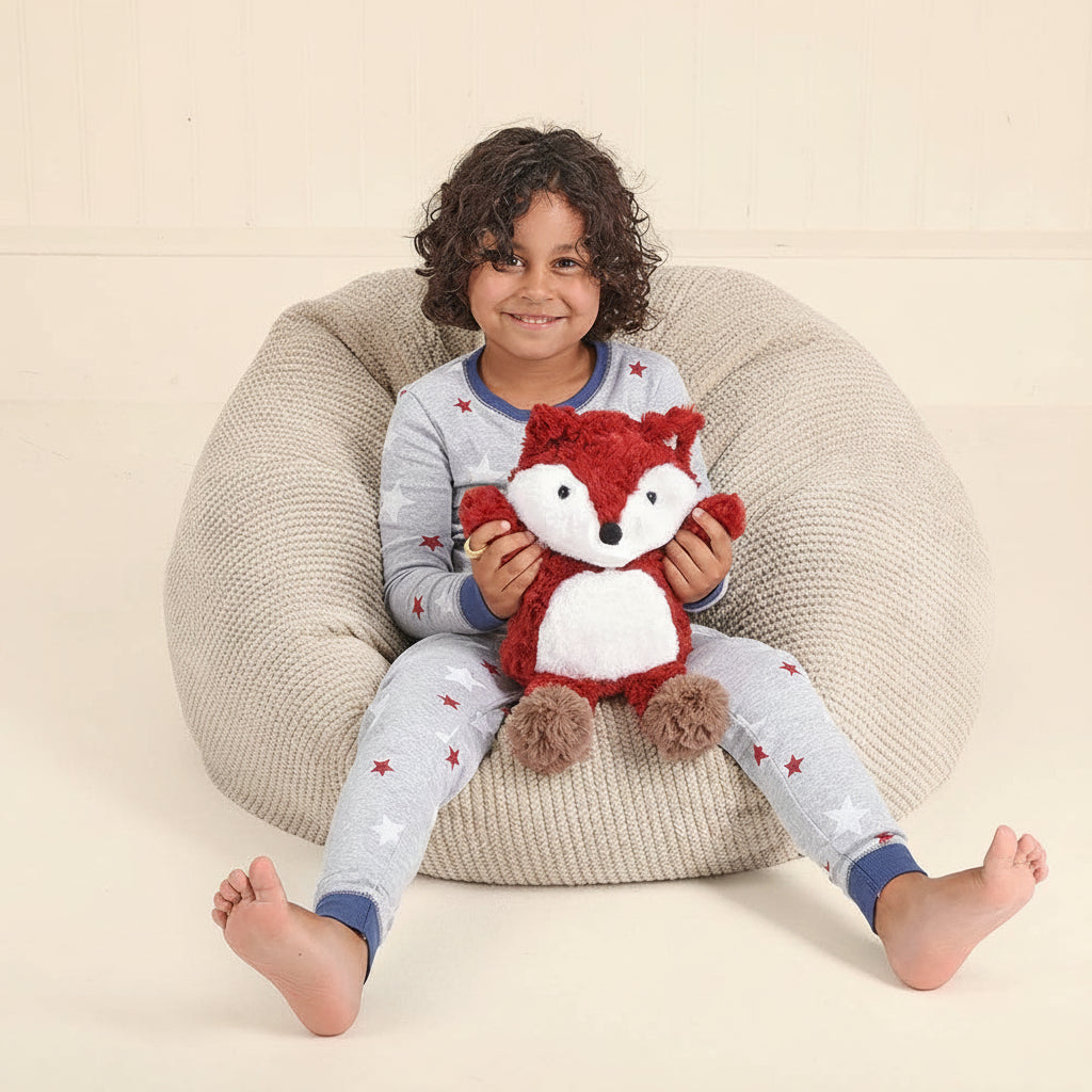 Child sitting on a cream beanbag cuddling the red fox Snuggable Hottie