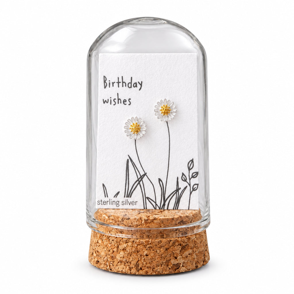 White daisy stud earrings on birthday wishes card inside glass terrarium held in hand