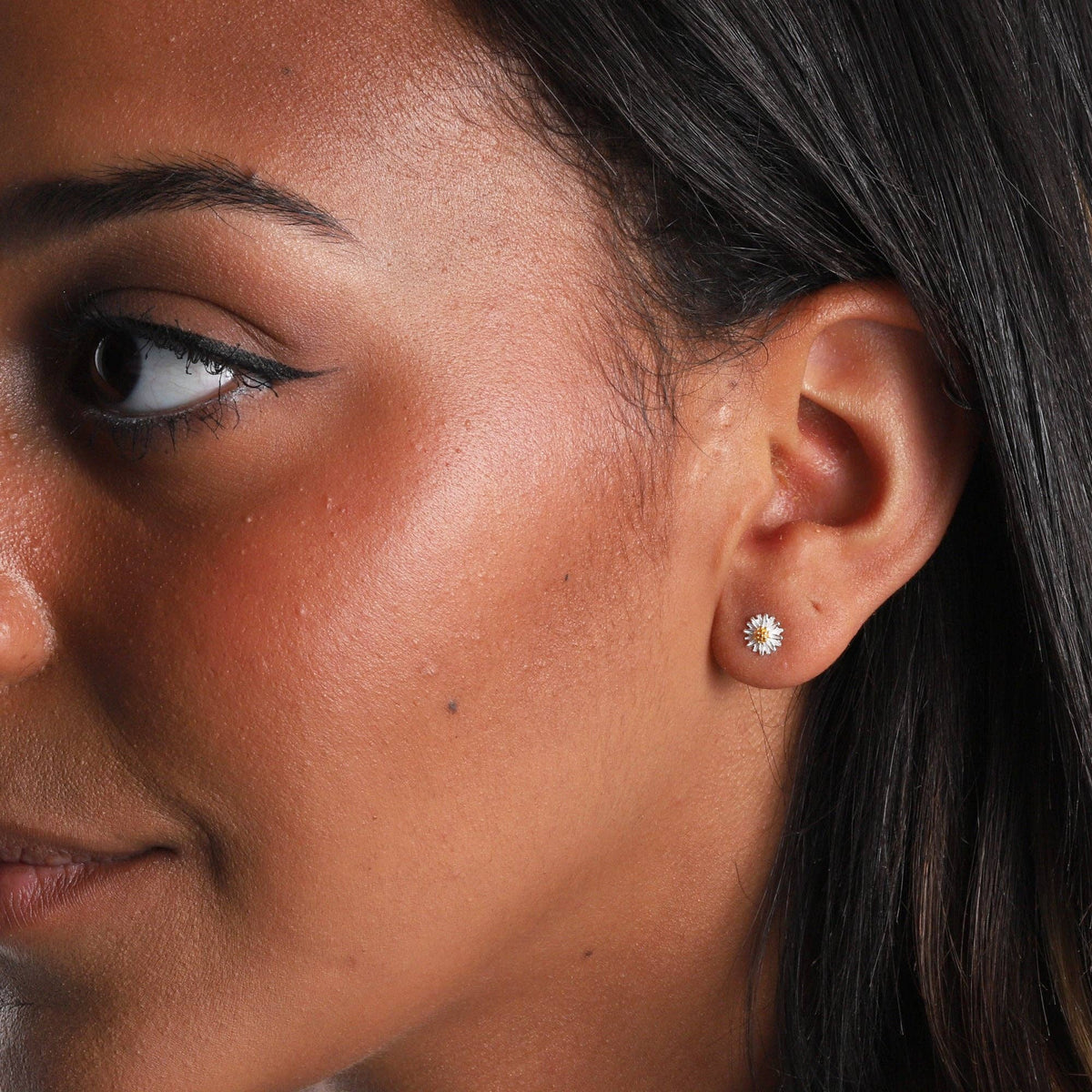 Woman wearing white daisy stud earring in lifestyle close-up