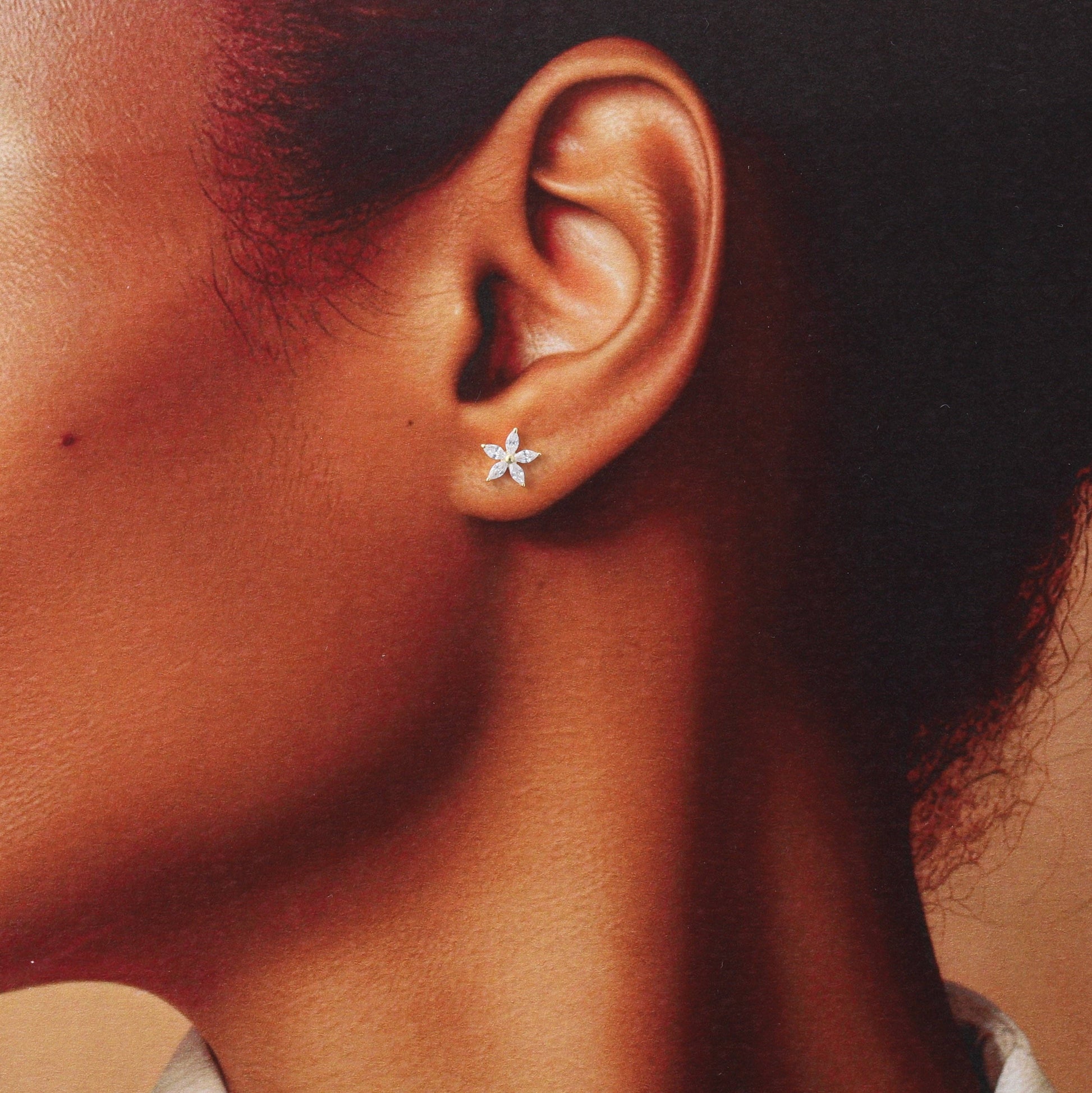 Woman wearing gold crystal flower stud earring in lifestyle close-up