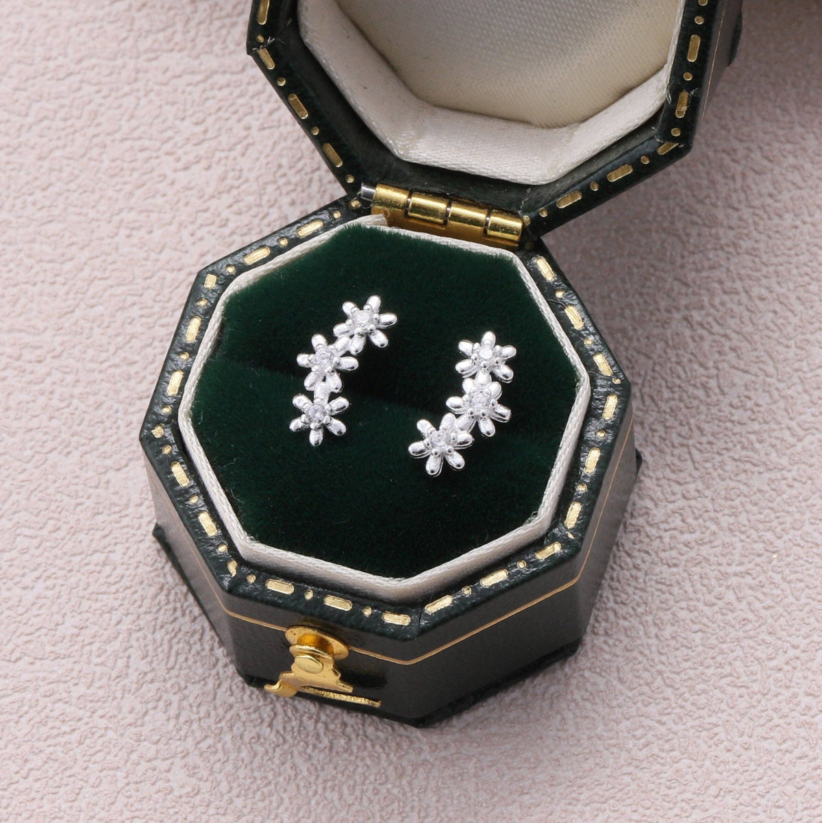 Clear crystal flower earrings displayed in dark teal octagonal jewellery box