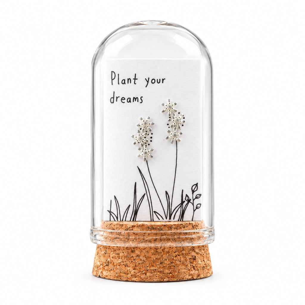 Clear crystal flower stud earrings on card inside glass terrarium held in hand