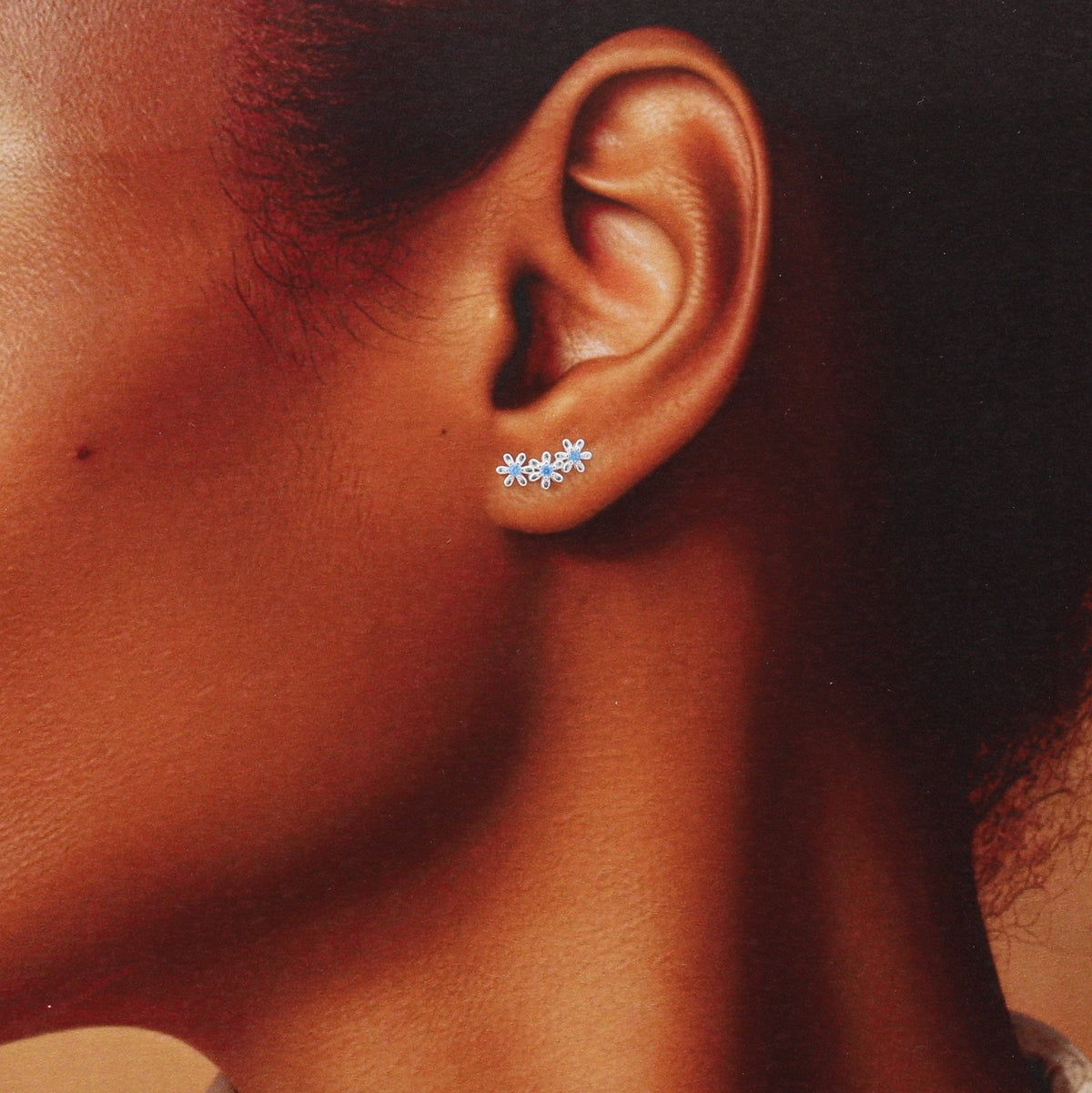 Blue crystal flower earrings worn in a curve on the earlobe