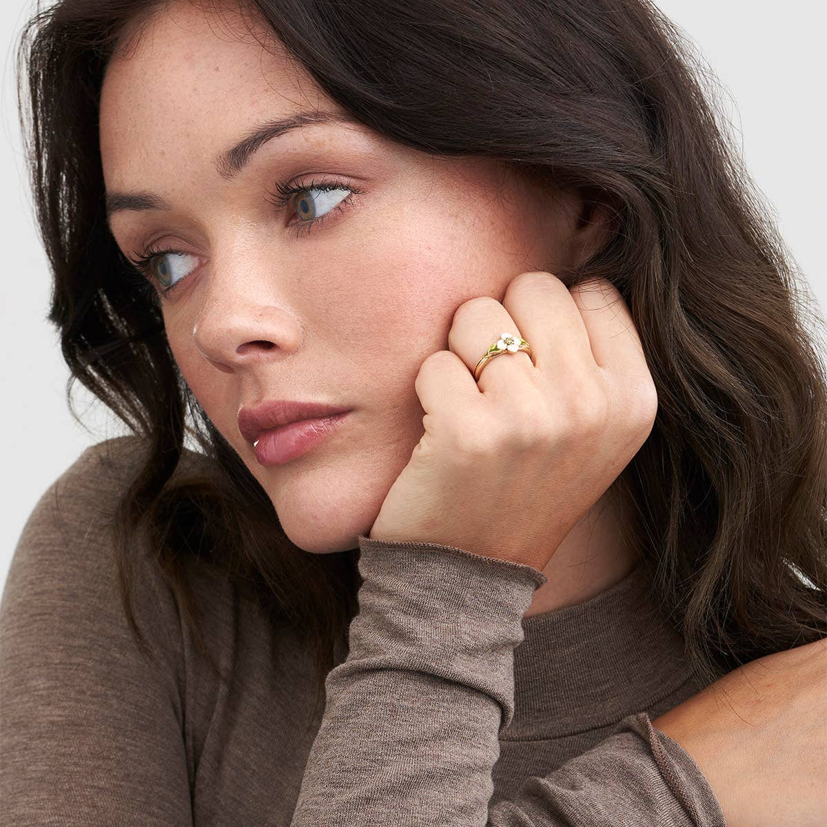 Woman wearing the Poppy Anemone flower ring, resting her chin on her hand