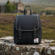 Black herringbone Harris Tweed Mini Jura backpack on stone wall in the Highlands
