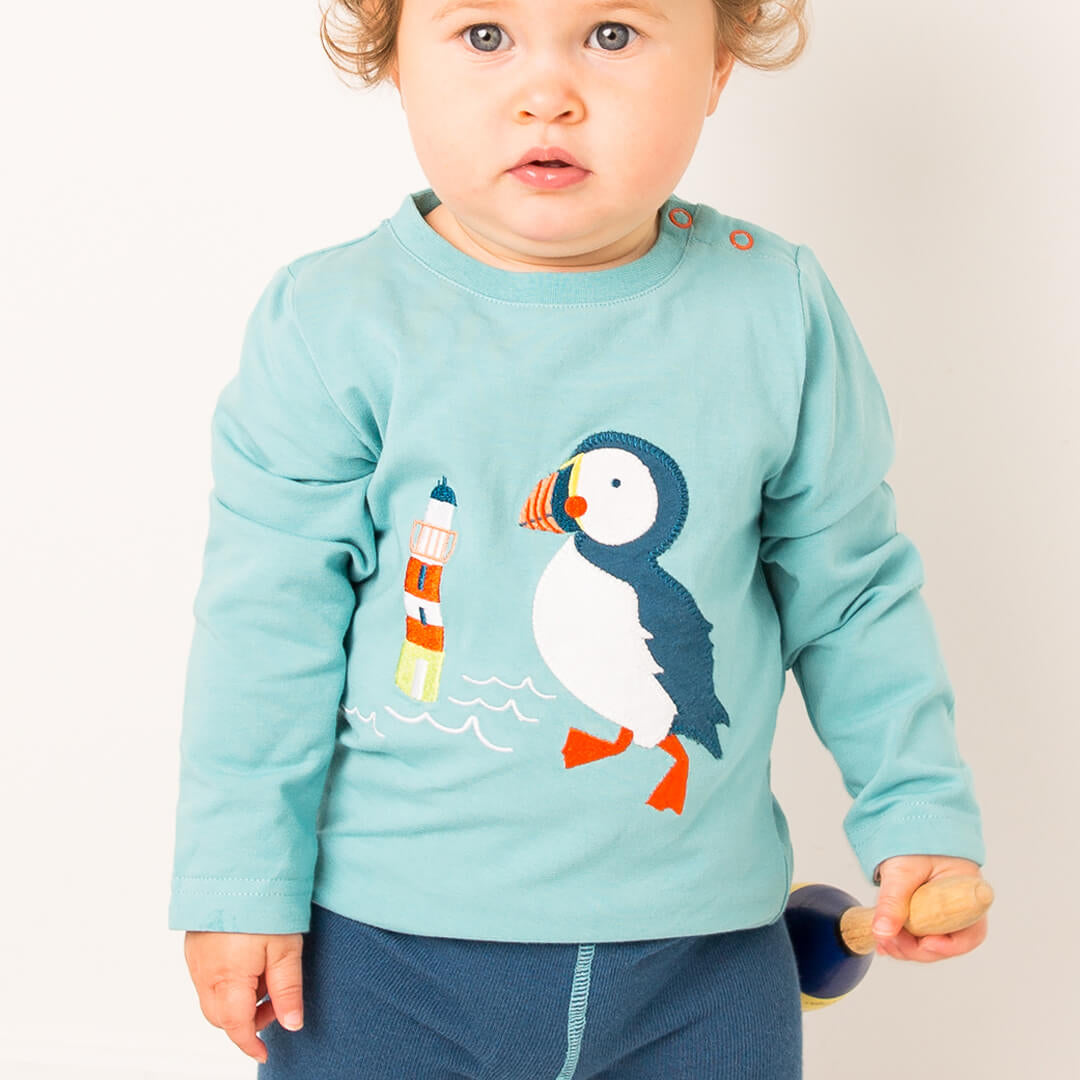 Toddler wearing the aqua Kenzie the Puffin long sleeve top and navy leggings