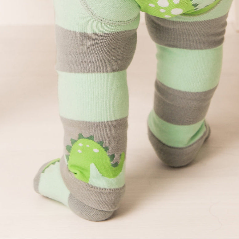 Close up of the striped Nessie socks on a standing baby beside a chair