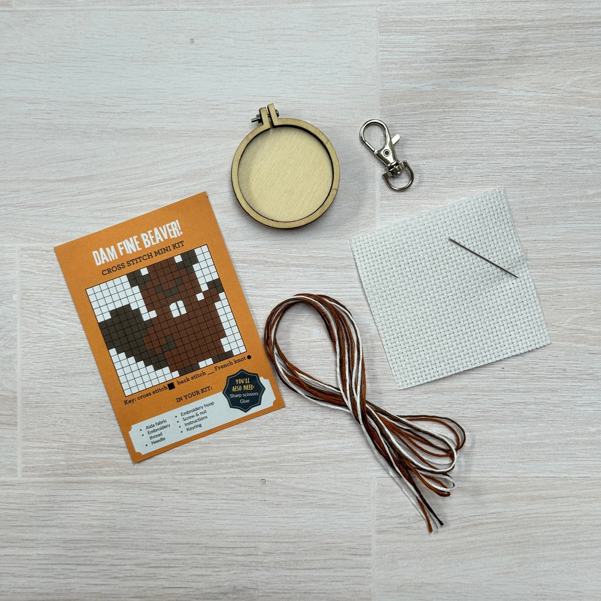 Beaver cross stitch kit contents laid out on pale wood