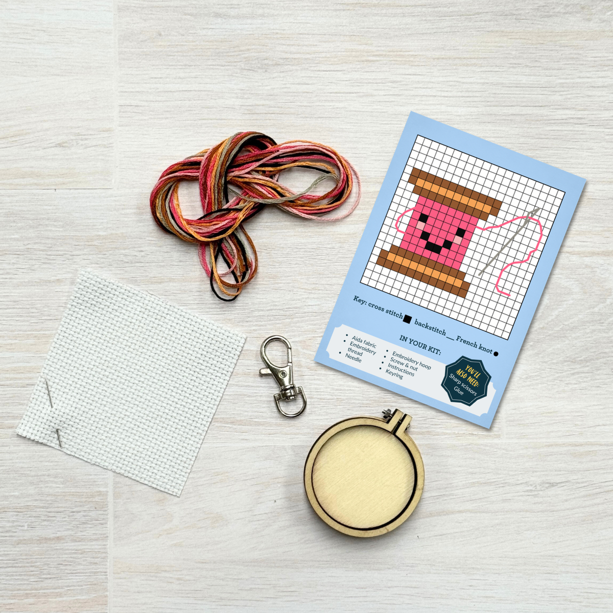 Cotton reel cross stitch kit contents laid out on pale wood