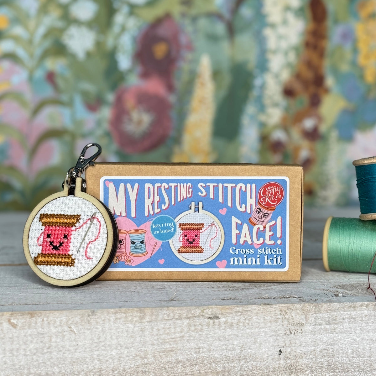 Cotton reel cross stitch keyring beside its matchbox with thread spools