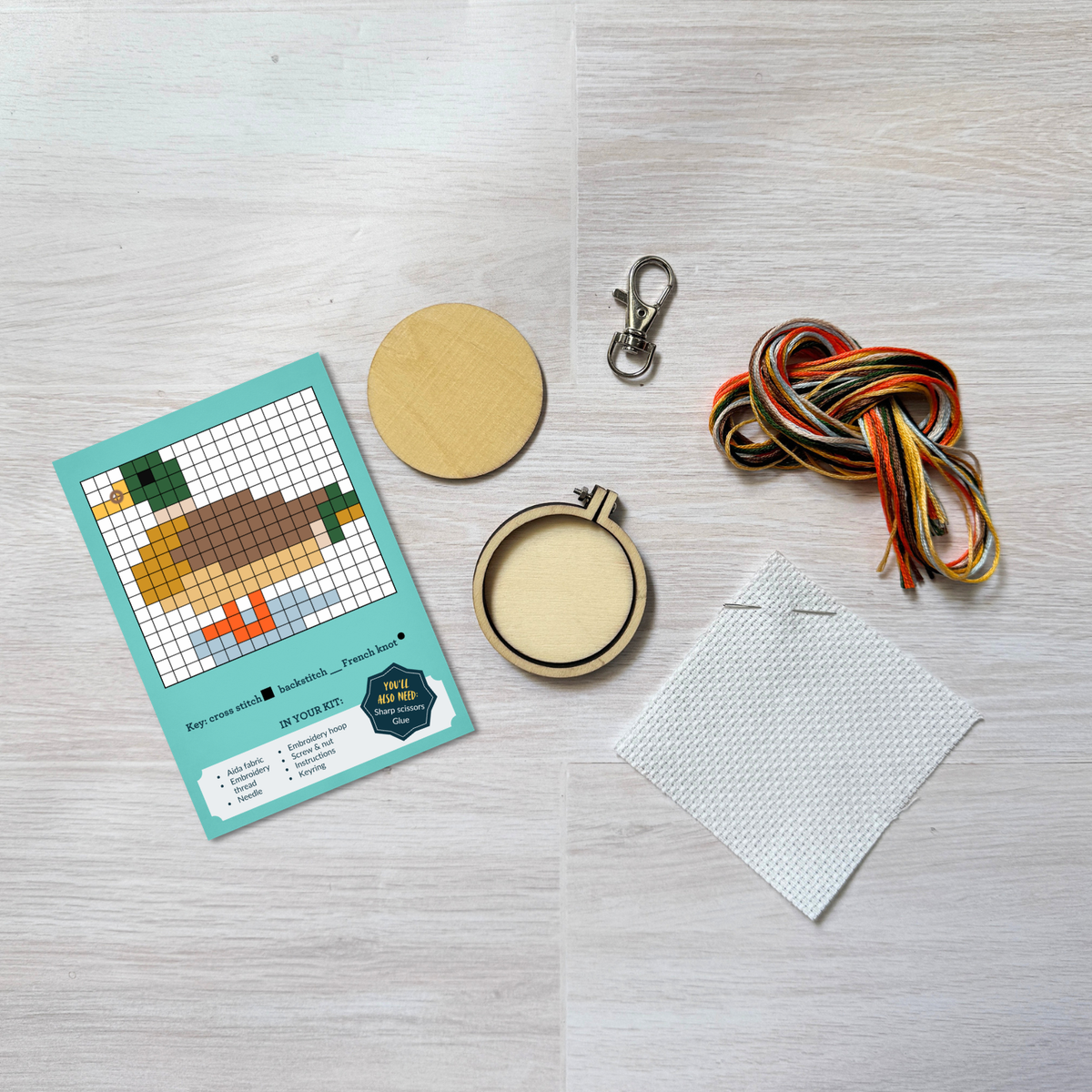 Duck cross stitch kit contents laid out on pale wood