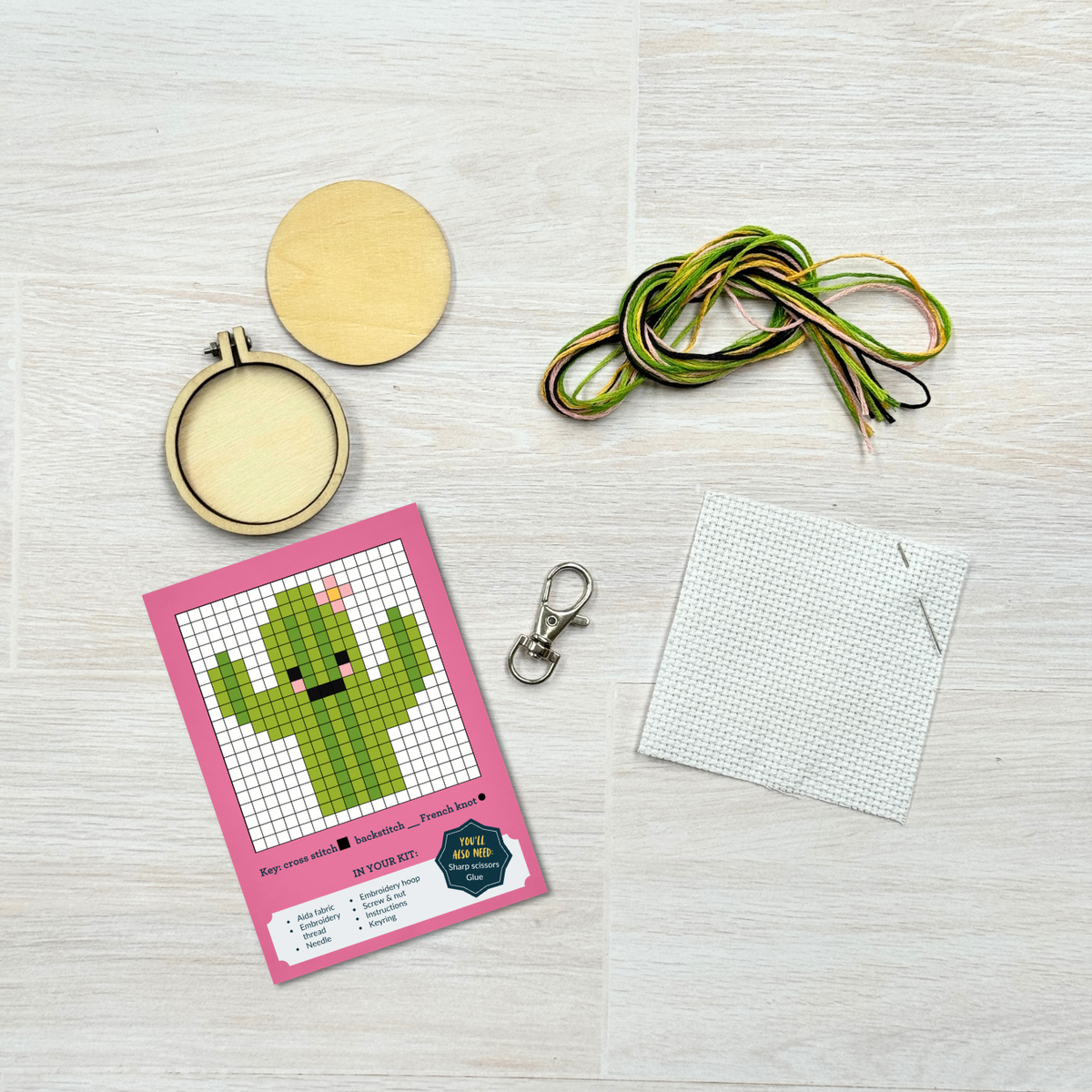 Cactus cross stitch kit contents laid out on pale wood