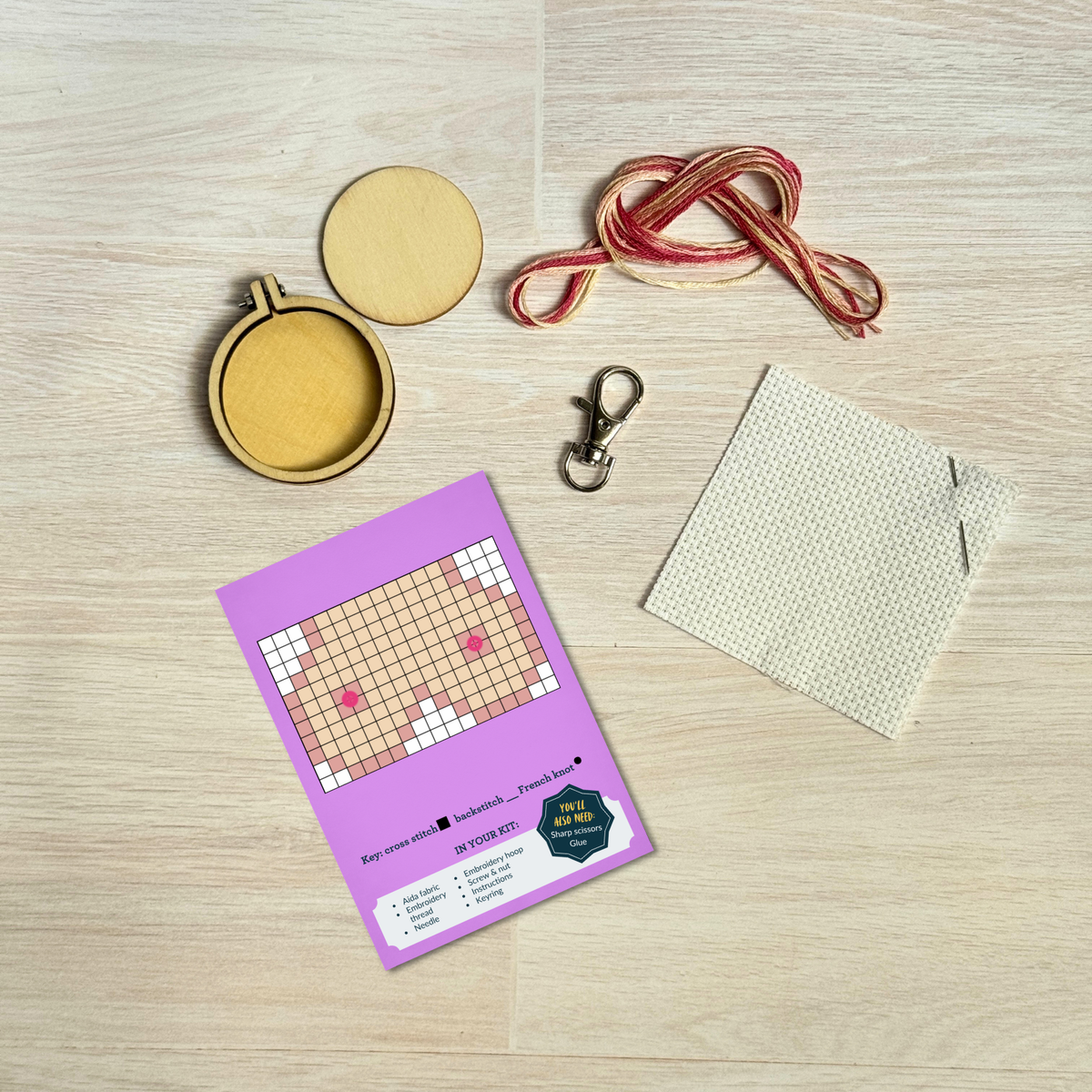 Cheeky cross stitch kit contents laid out on pale wood