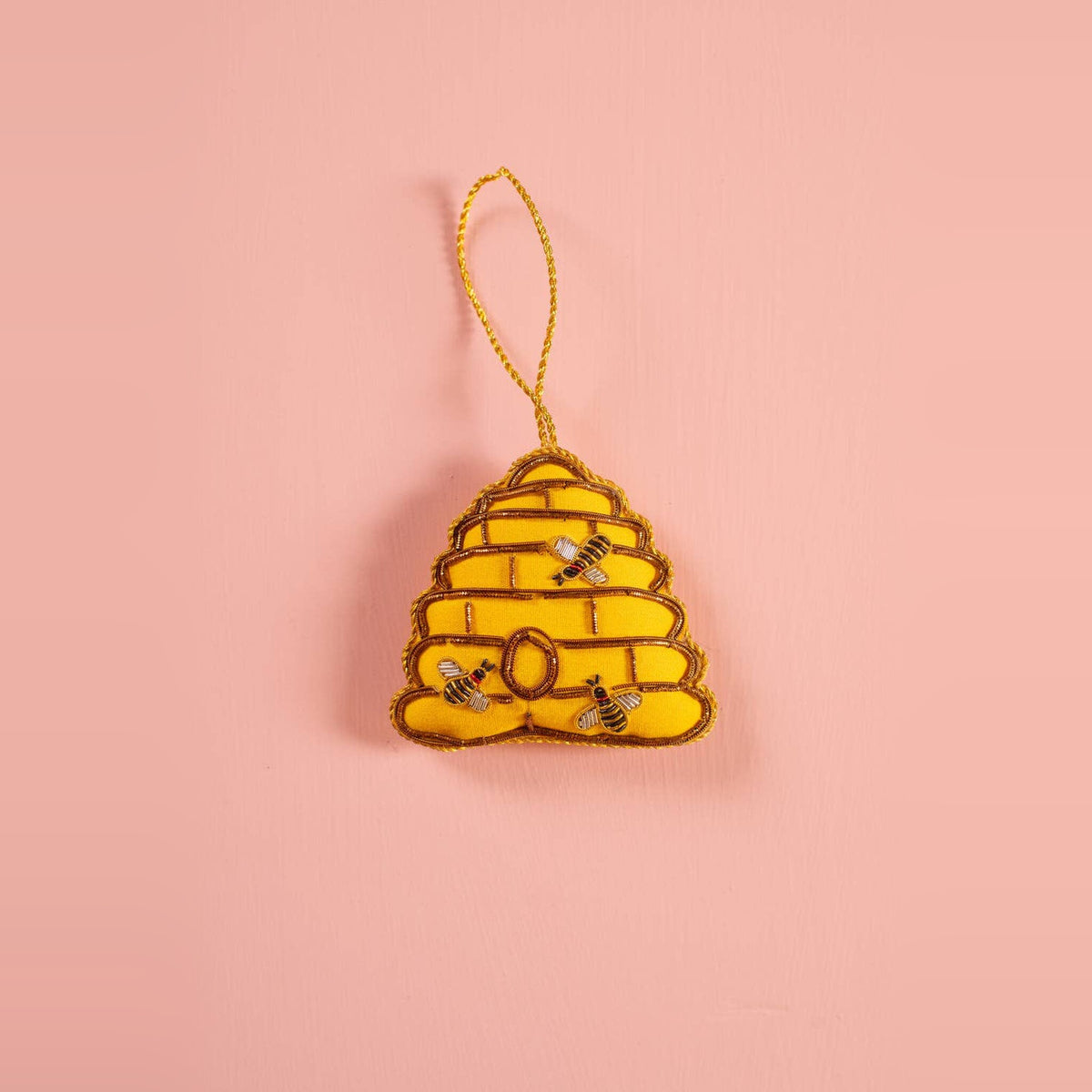 Beehive embroidered decoration in yellow and gold with stitched bees on a peach background