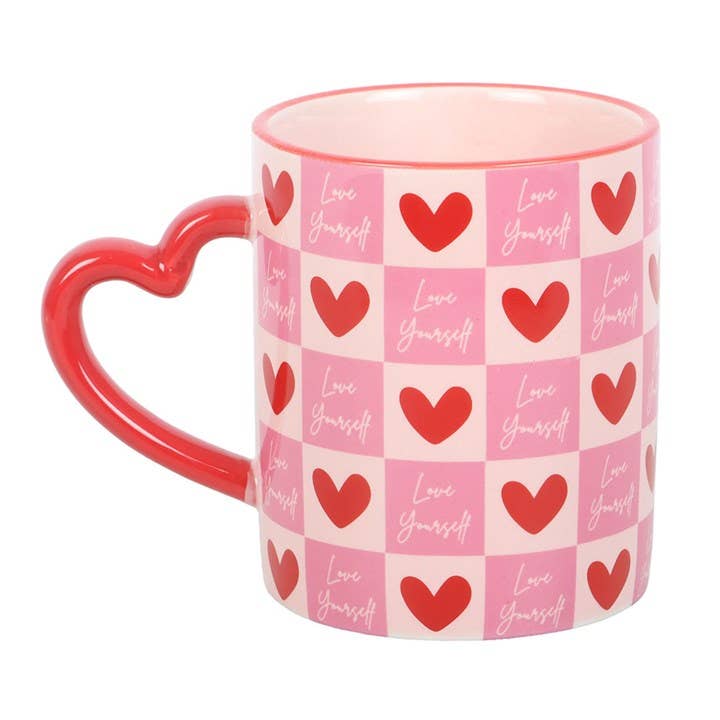 Pink checkerboard Love Yourself mug with red heart handle on white background