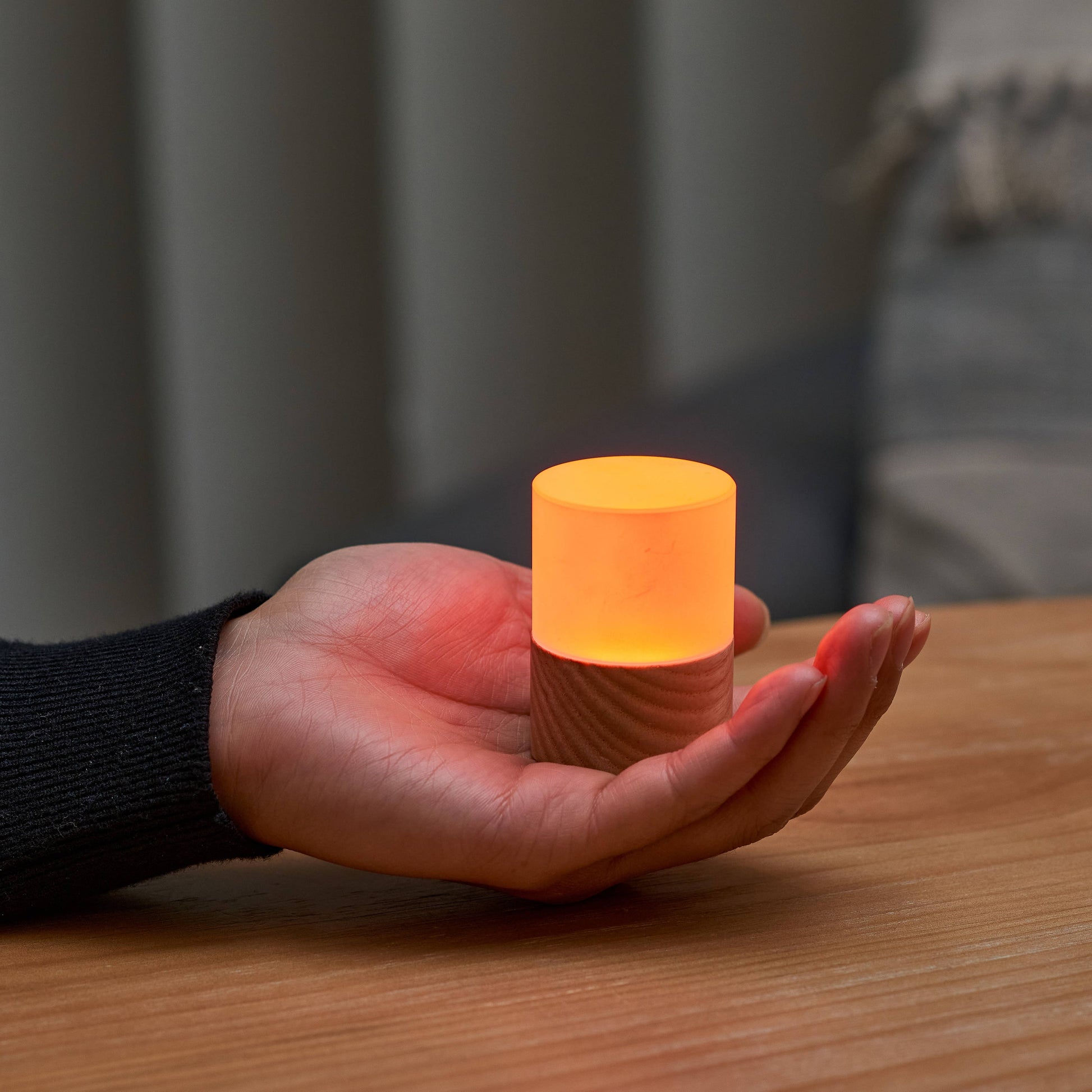 Lemelia mini light held in a palm glowing warm amber orange