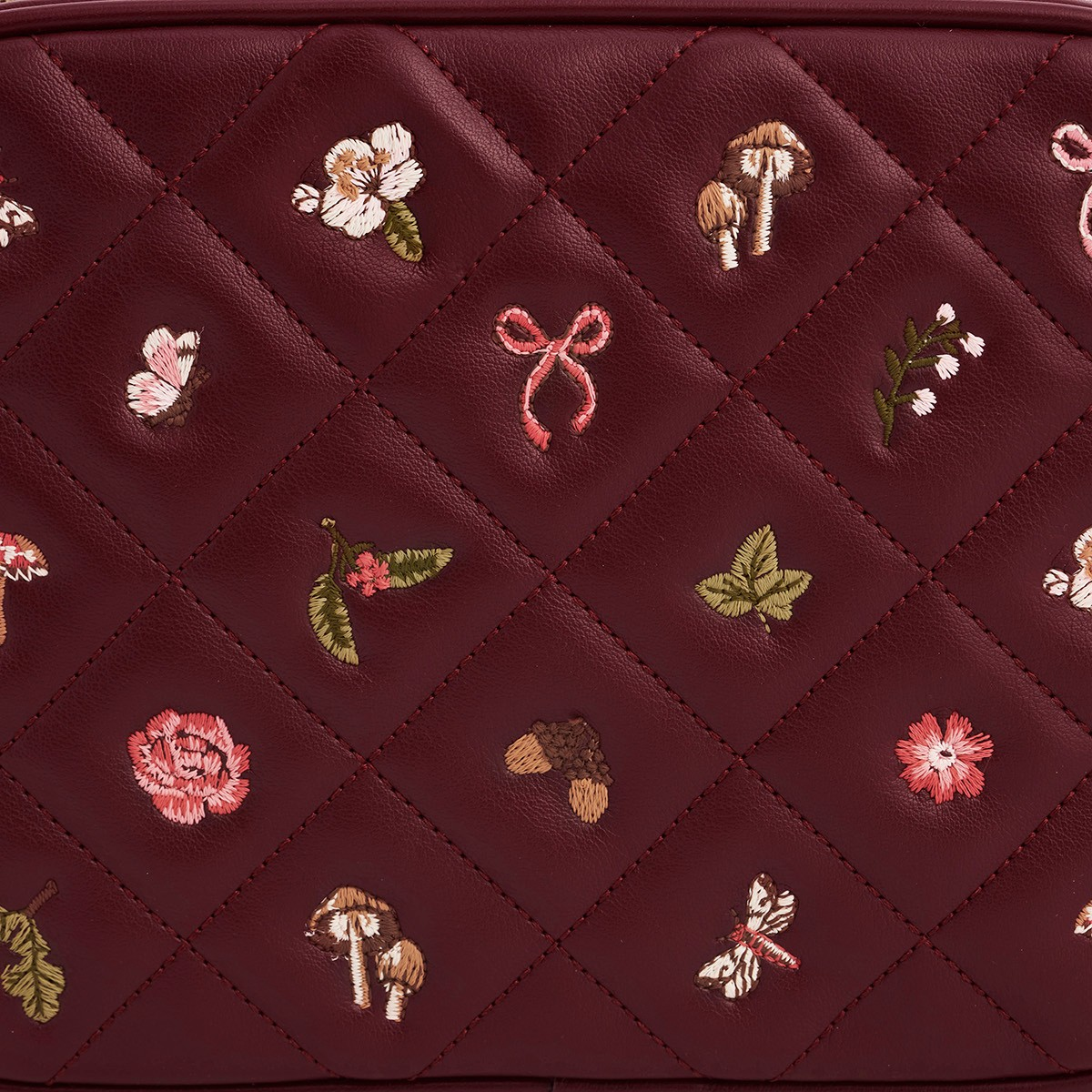 Close up of embroidered mushrooms and flowers on quilted faux leather
