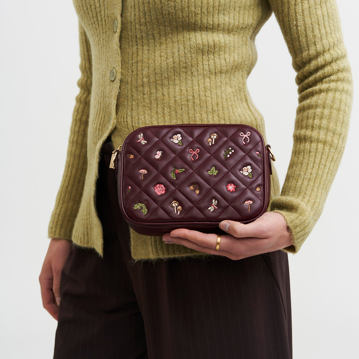 Model holding the burgundy quilted camera bag