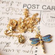 Dragonfly necklace and matching earrings styled on vintage postcards with brass bell