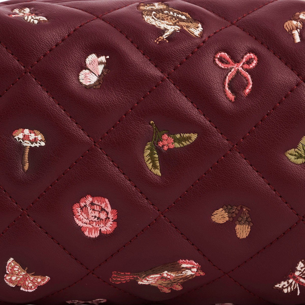 Close up of embroidered butterflies and mushrooms on quilted faux leather