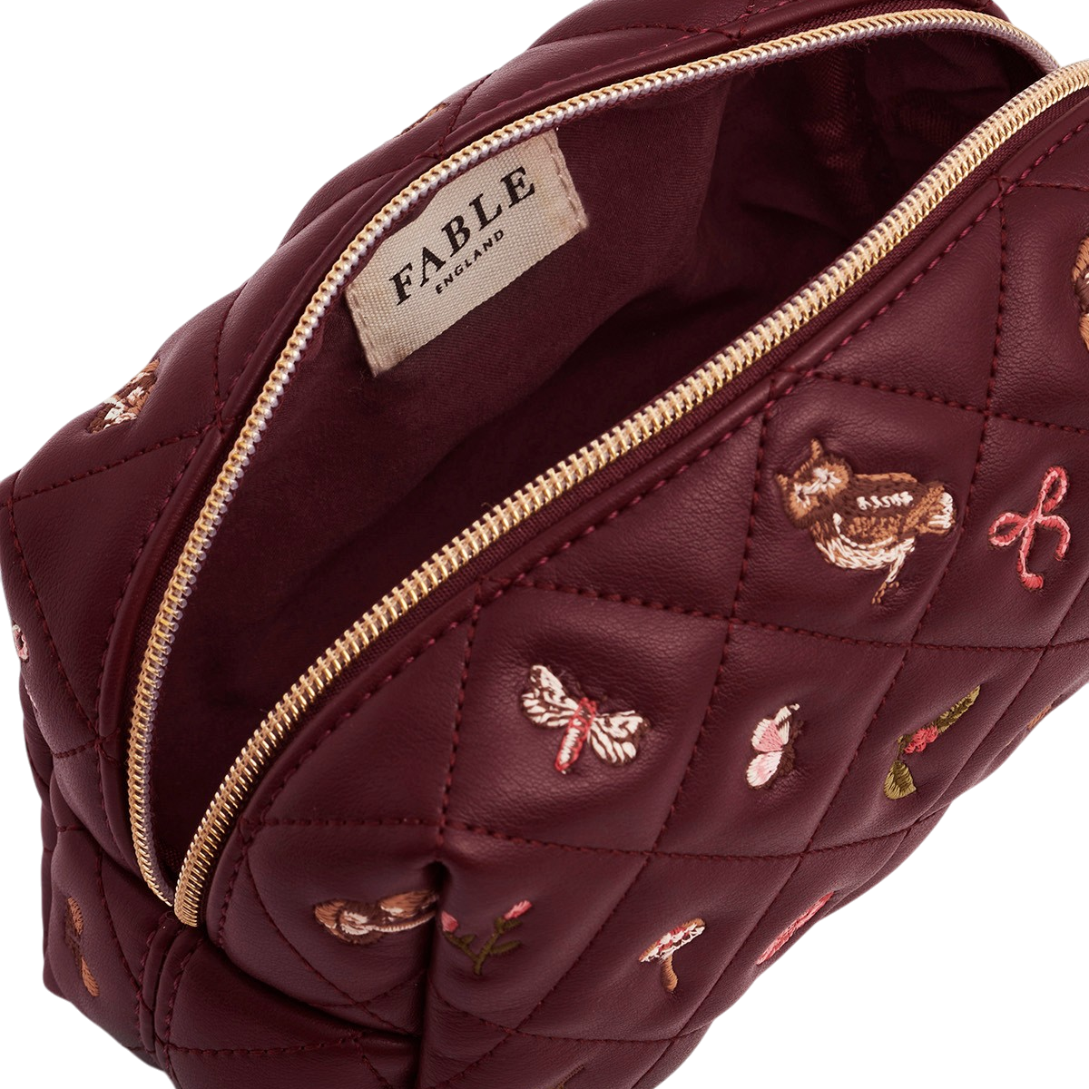 Burgundy quilted pouch open showing the zip and Fable label
