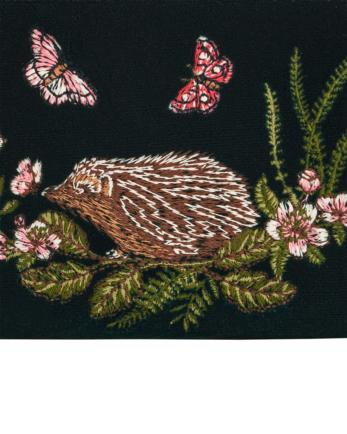 Close up of the embroidered hedgehog, blossoms and butterflies