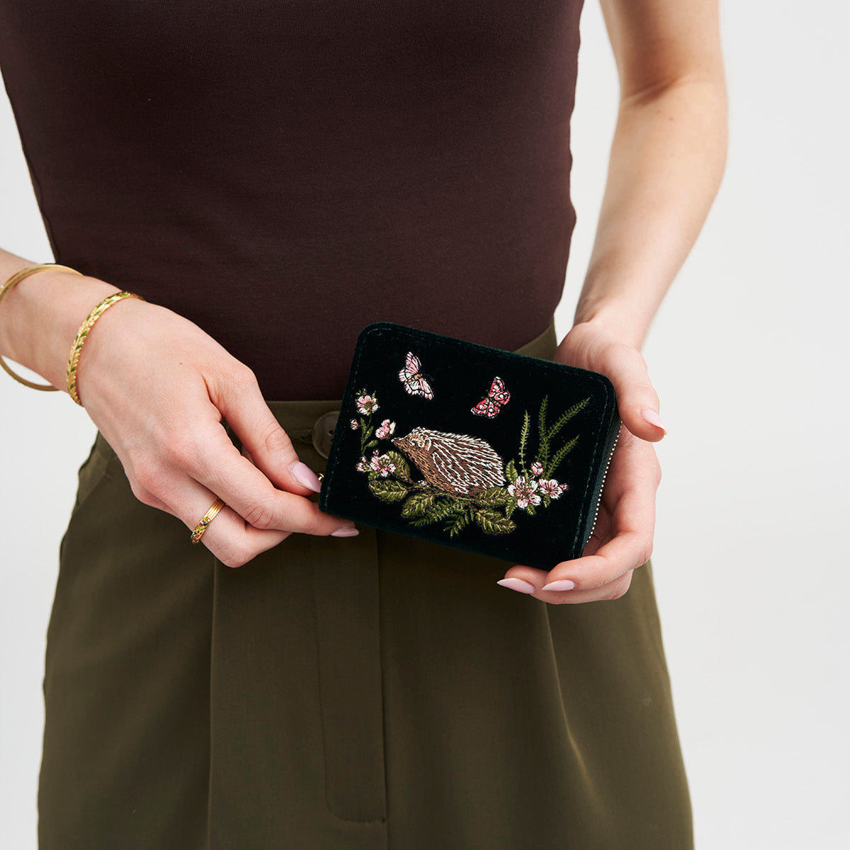 Model holding the hedgehog embroidered green velvet purse
