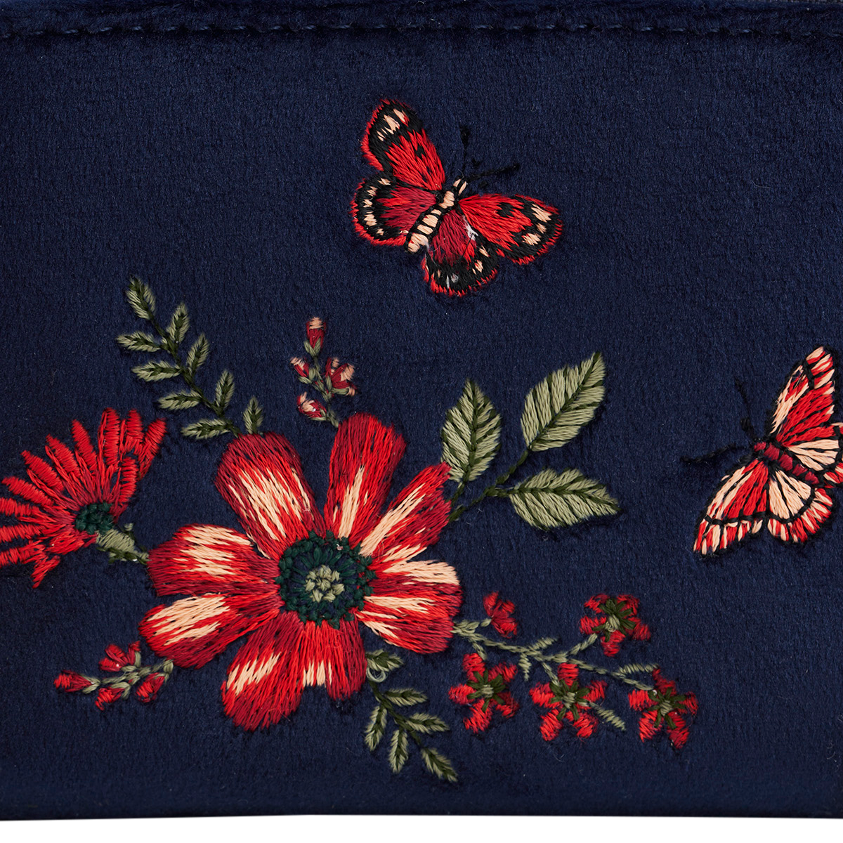 Close up of red flower and butterfly embroidery on navy velvet