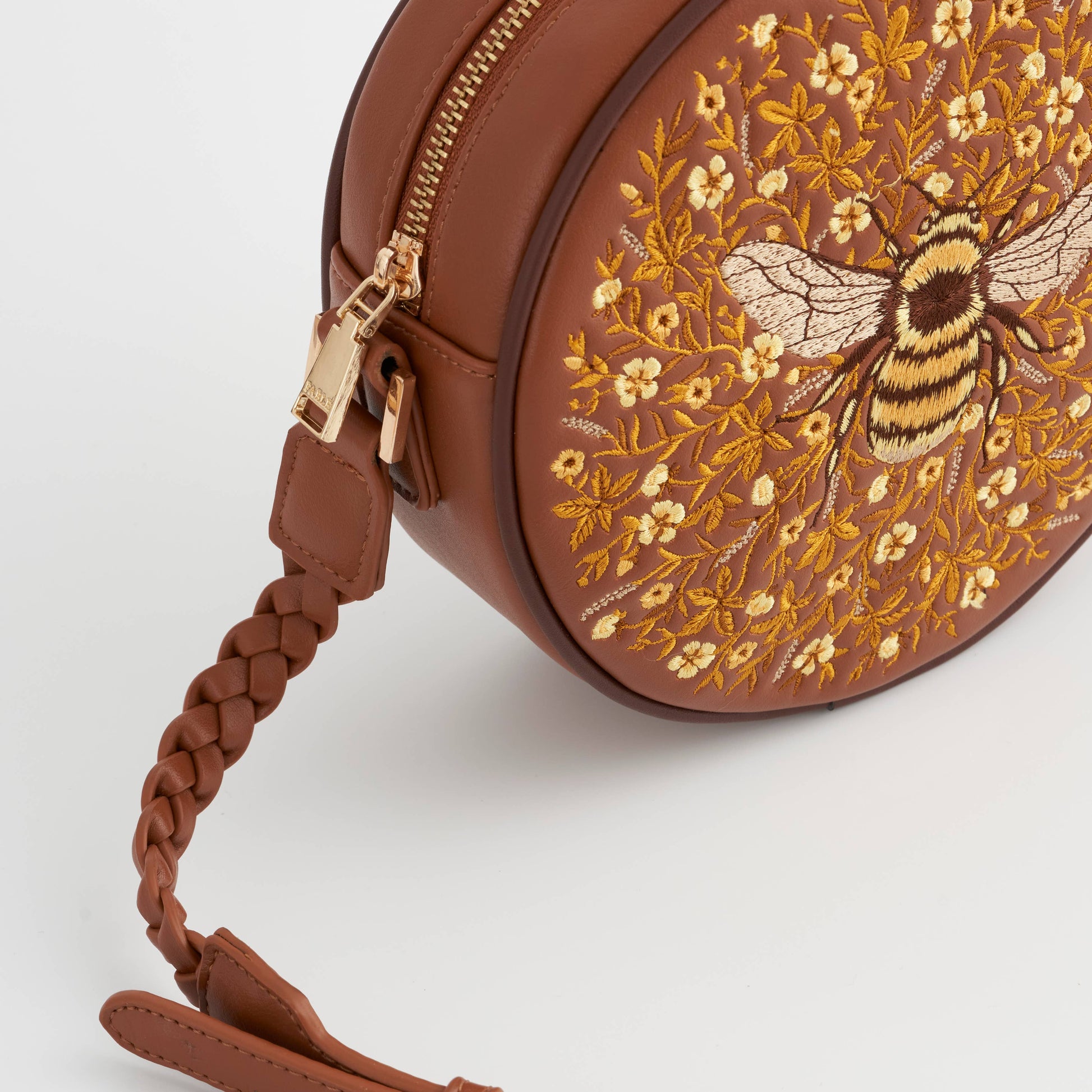Close up of the purse zip pull and plaited tan shoulder strap