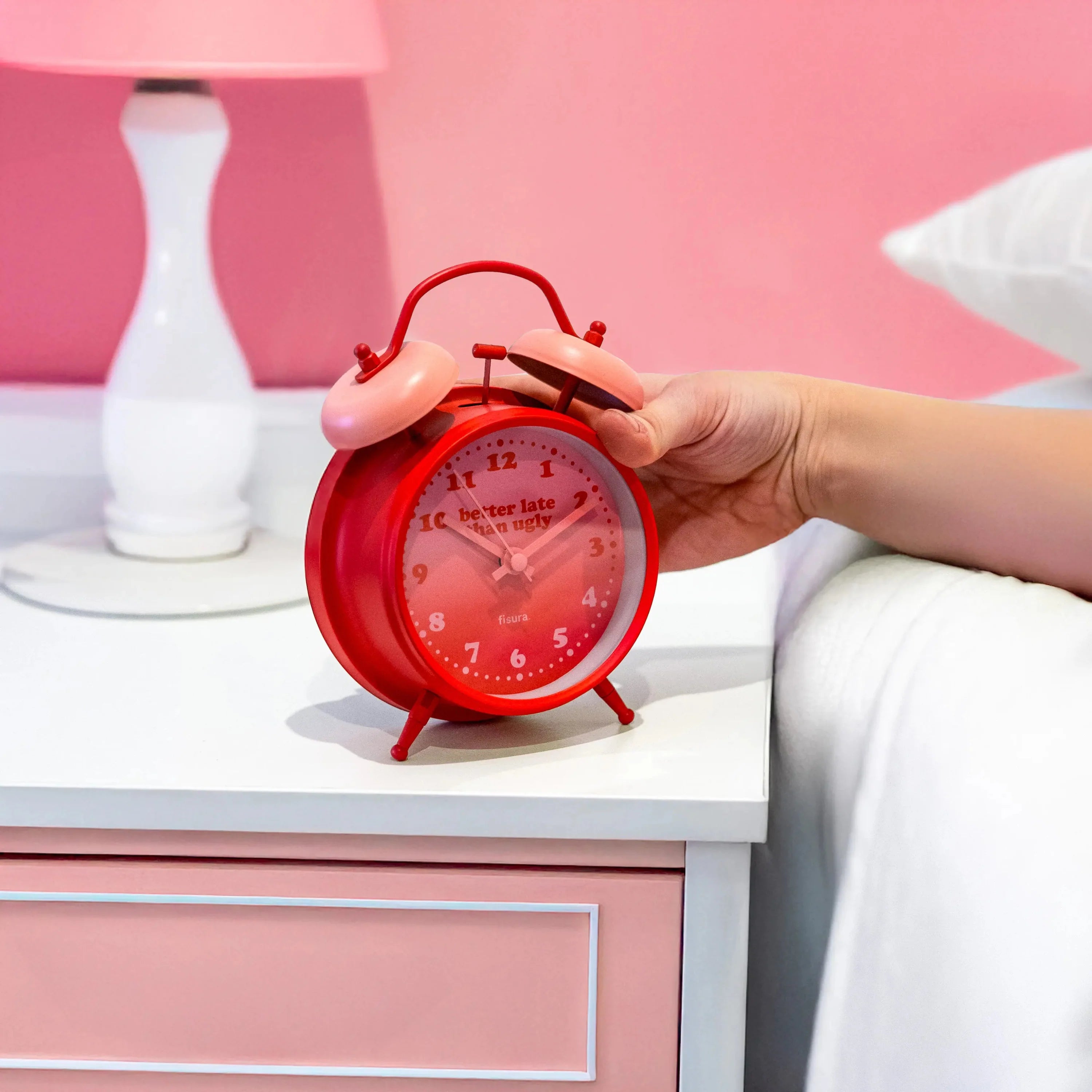 Person reaching for the red twin-bell alarm clock while wearing an eye mask