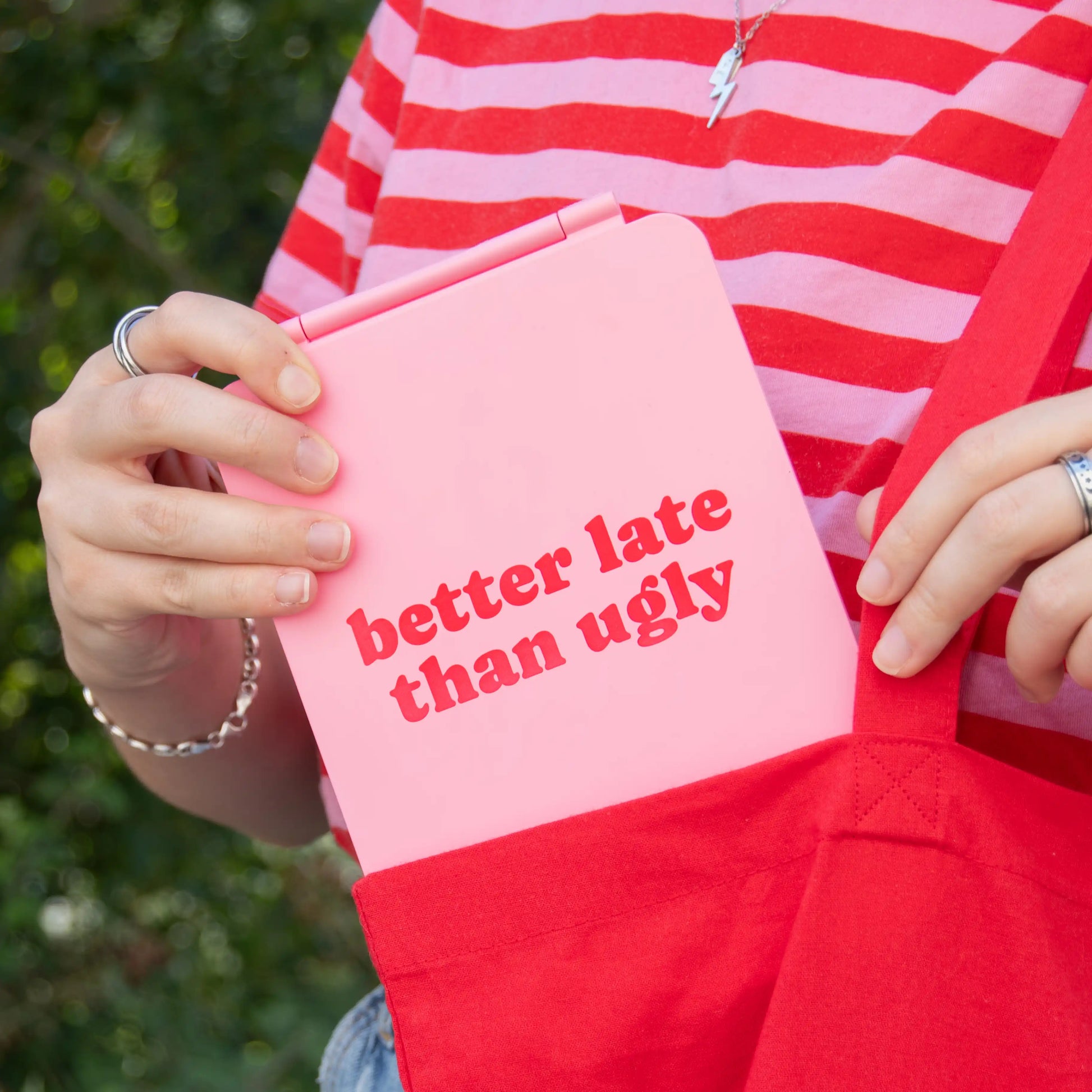 Hand holding the closed pink mirror showing the better late than ugly text