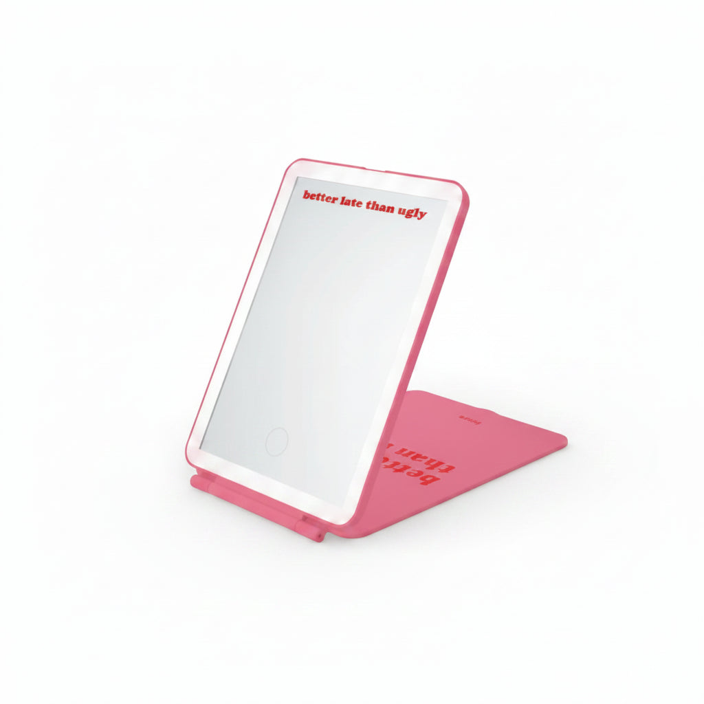 Pink folding LED travel mirror open, shown beside its packaging