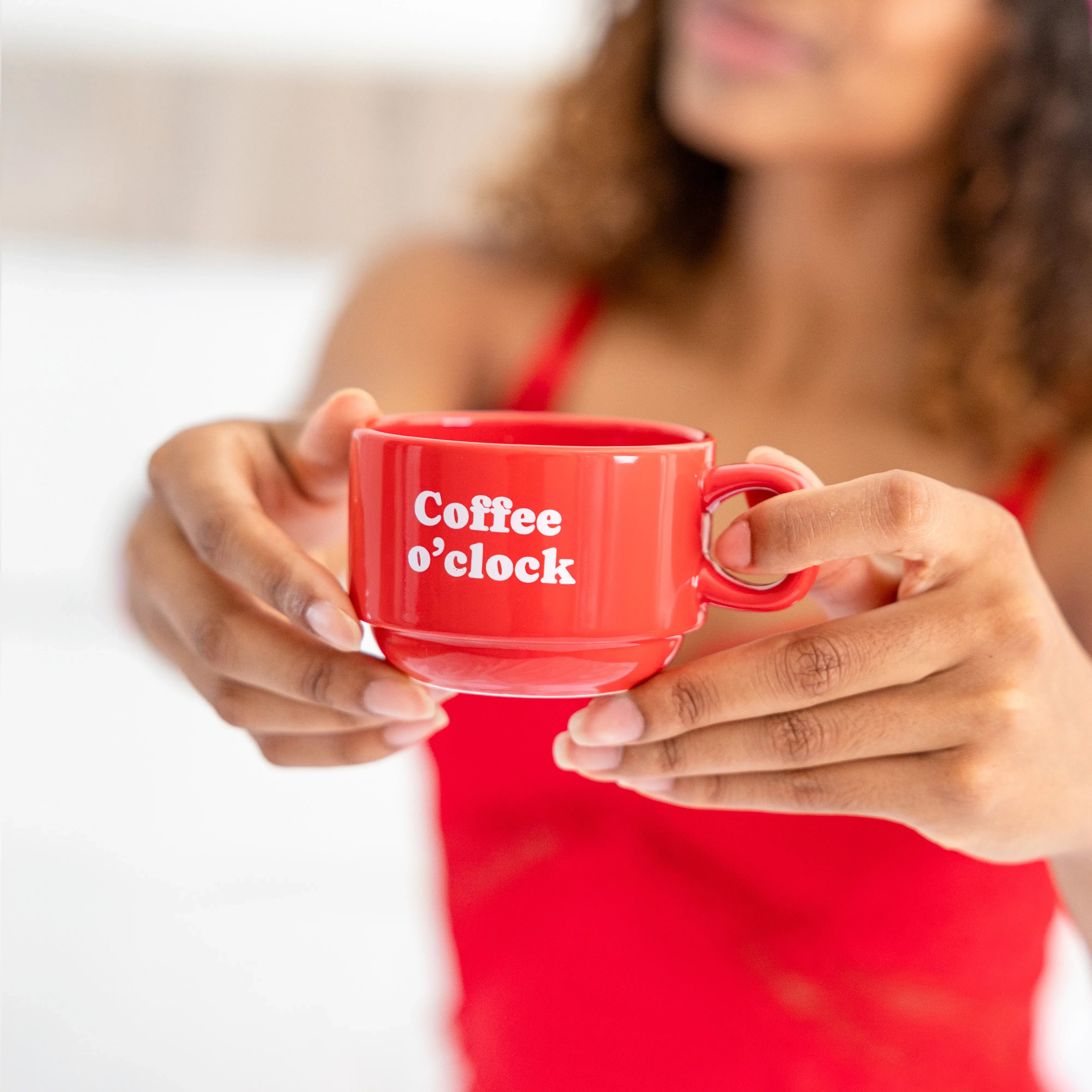 Person in red holding one of the small red Coffee o'clock mugs