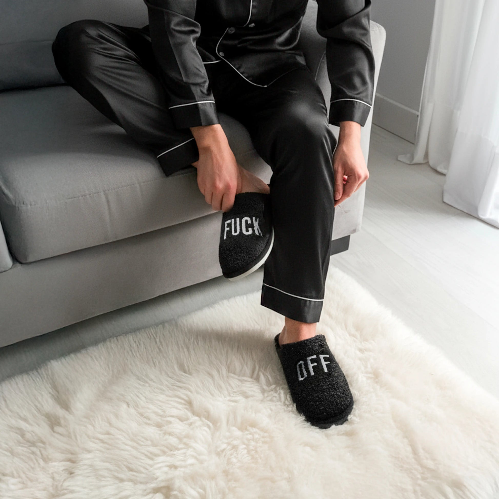 Person sitting on a sofa wearing the black slippers