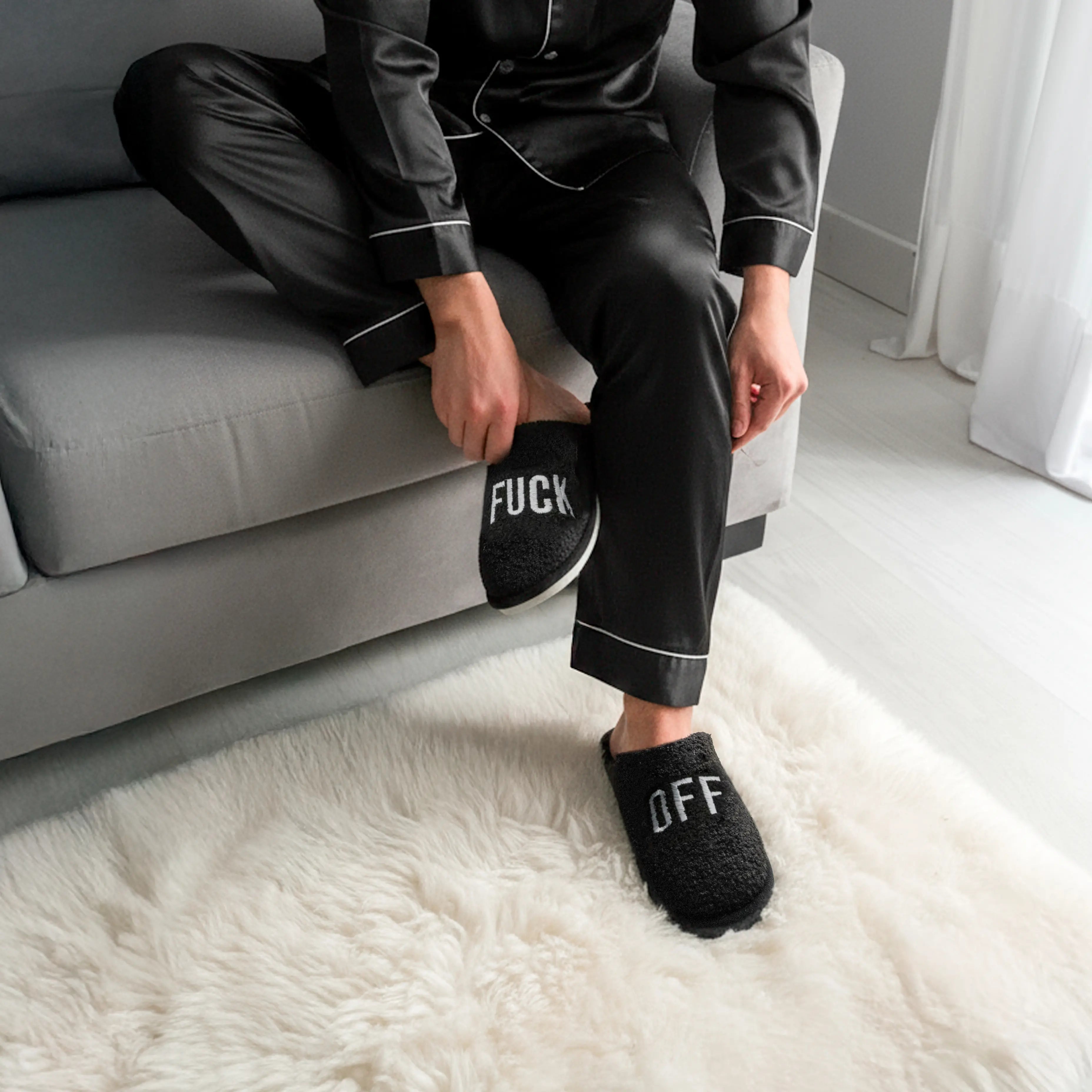 Person sitting on a sofa wearing the black slippers