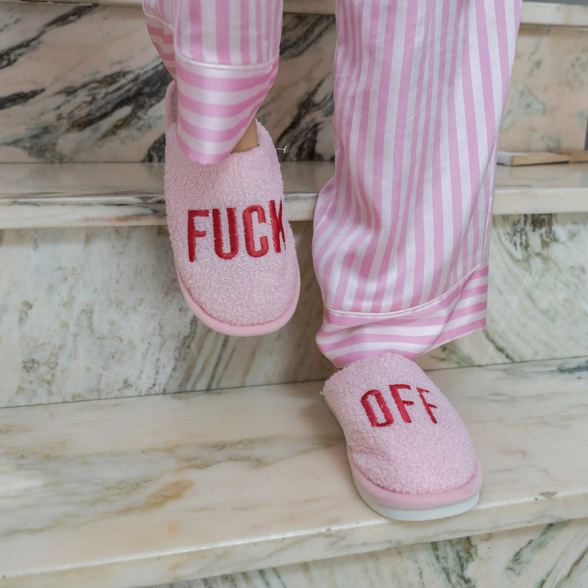 Pink slippers being worn on a pale marble floor