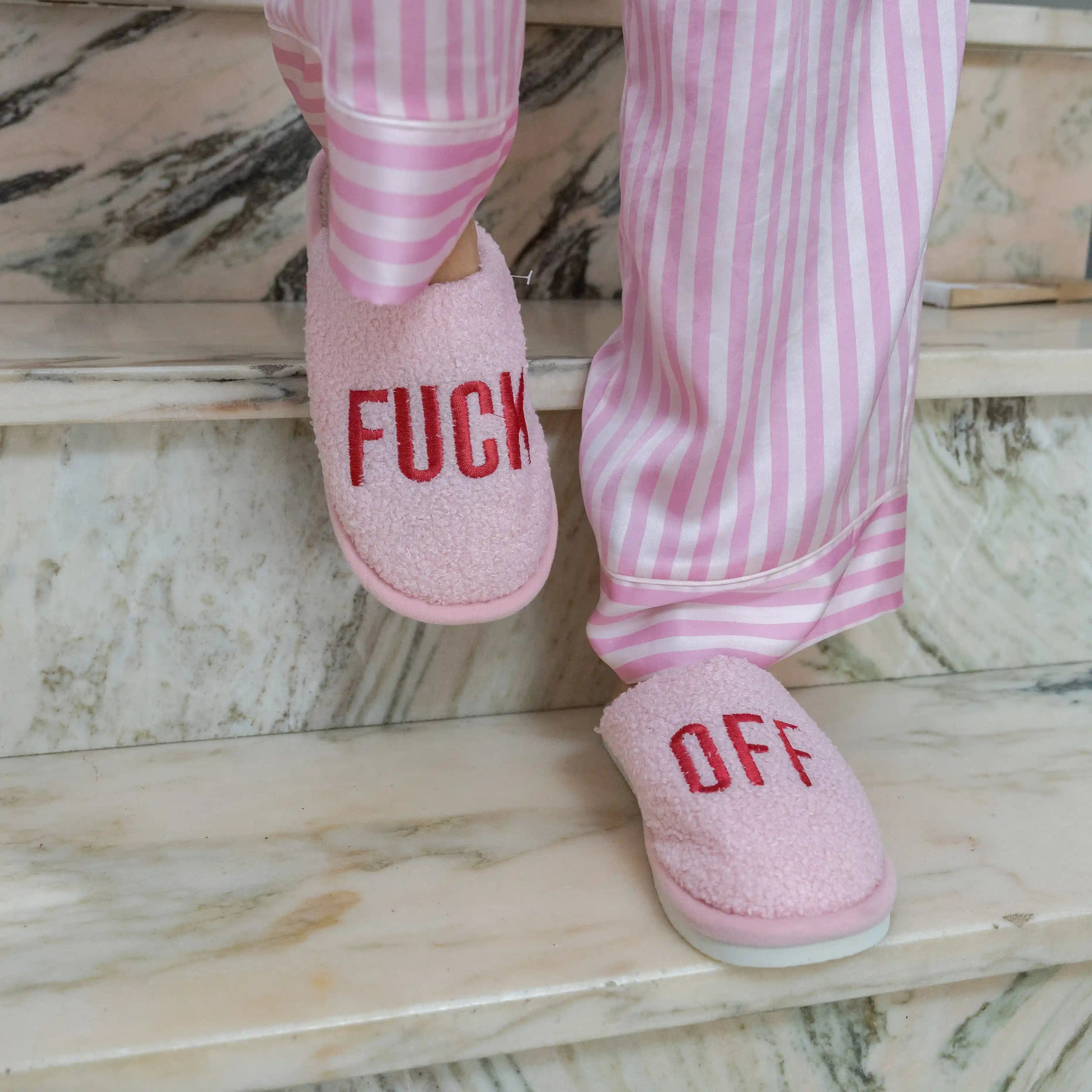 Pink slippers being worn on a pale marble floor